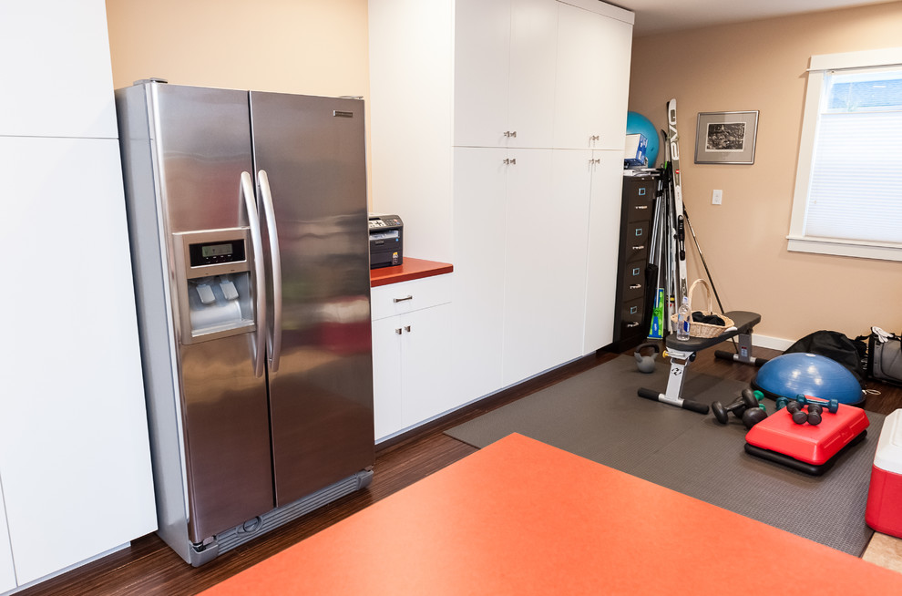 Example of a mid-sized eclectic galley bamboo floor utility room design in Portland with an utility sink, flat-panel cabinets, white cabinets, laminate countertops, orange walls and a side-by-side washer/dryer