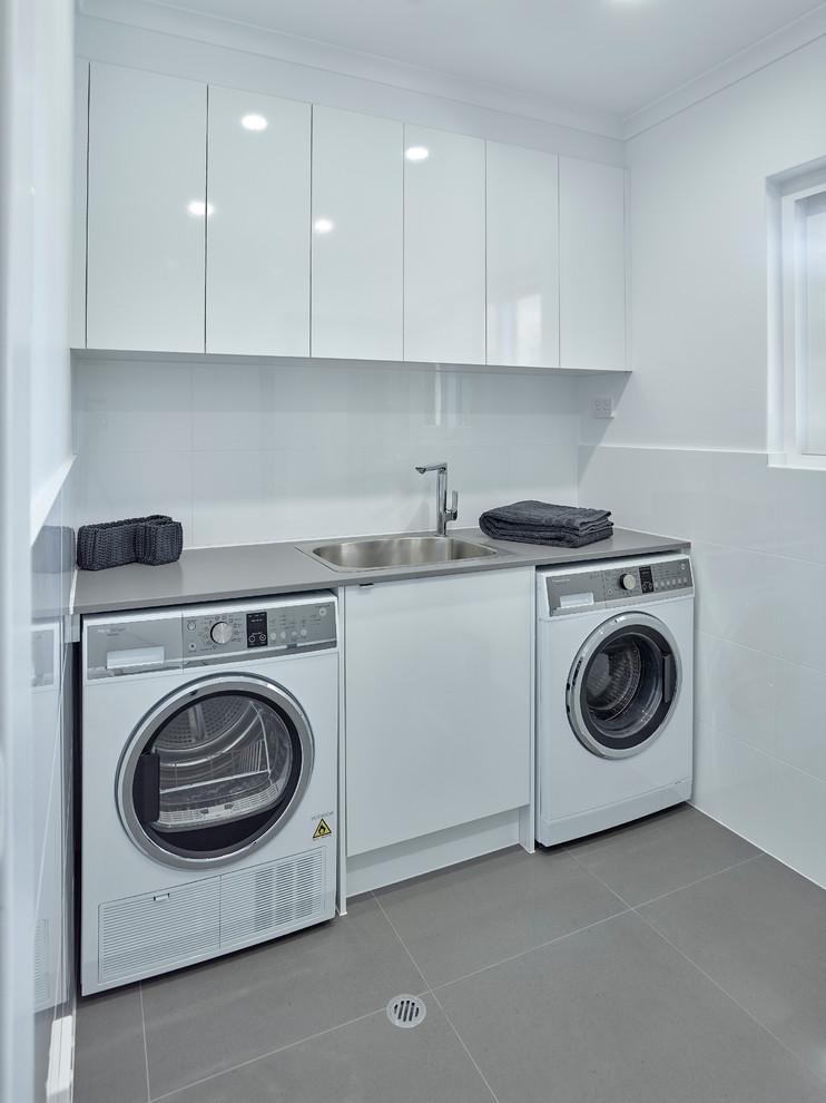 Ispirazione per una sala lavanderia minimal di medie dimensioni con lavello da incasso, ante bianche, top in laminato, pareti bianche e lavatrice e asciugatrice affiancate