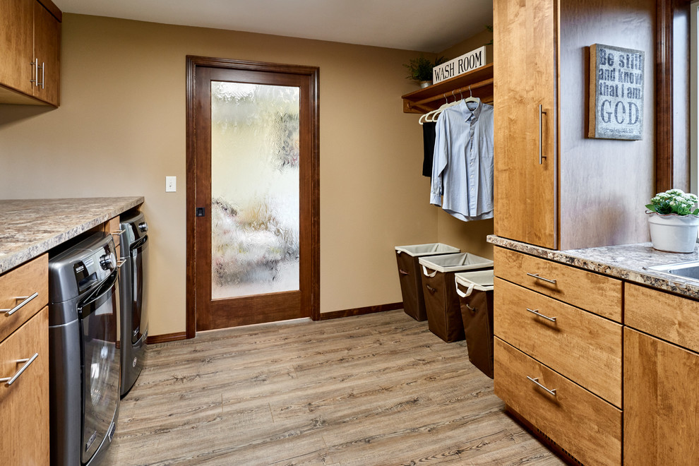 Galley utility room in Other with a built-in sink, flat-panel cabinets, medium wood cabinets, laminate countertops, beige walls, laminate floors, a side by side washer and dryer, grey floors and beige worktops.