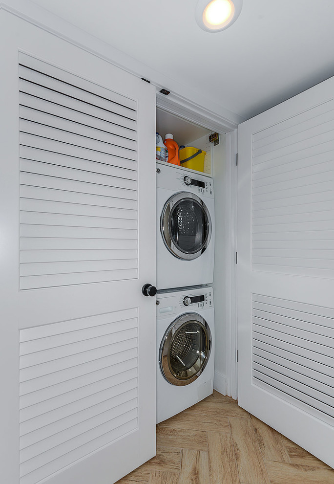 Example of a minimalist single-wall laundry closet design in Tampa with louvered cabinets, white cabinets, white walls and a stacked washer/dryer