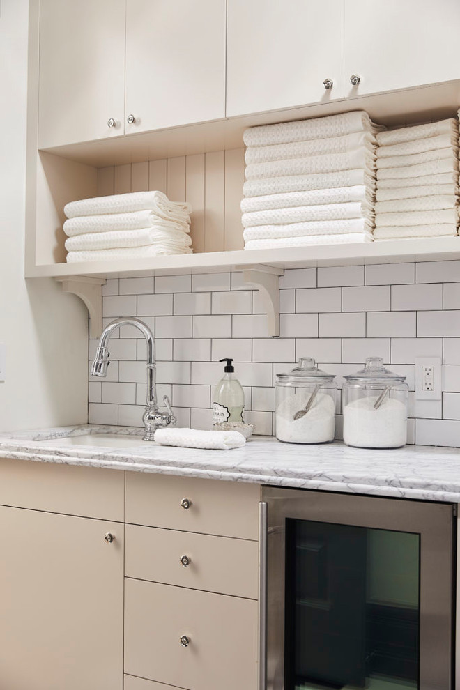 Immagine di una lavanderia tradizionale con lavello sottopiano, ante lisce, pareti bianche e top bianco