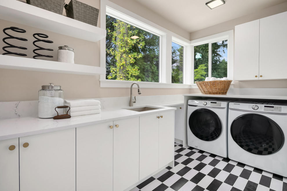 Große Moderne Waschküche in L-Form mit Unterbauwaschbecken, flächenbündigen Schrankfronten, weißen Schränken, Küchenrückwand in Weiß, Waschmaschine und Trockner nebeneinander und weißer Arbeitsplatte in Seattle