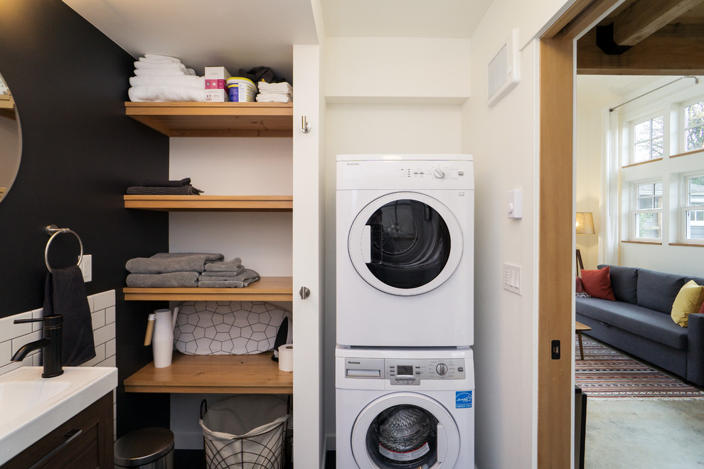 ポートランドにあるカントリー風のおしゃれな家事室 (L型、一体型シンク、黒い壁、上下配置の洗濯機・乾燥機) の写真