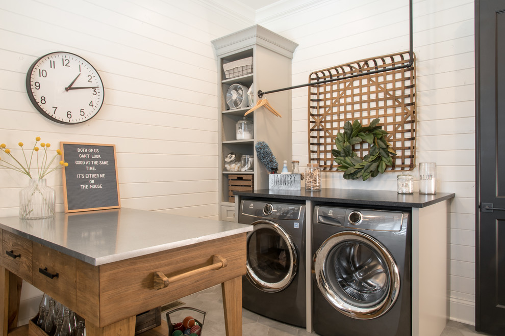 Ejemplo de lavadero clásico con puertas de armario grises, paredes blancas, lavadora y secadora juntas y encimeras grises