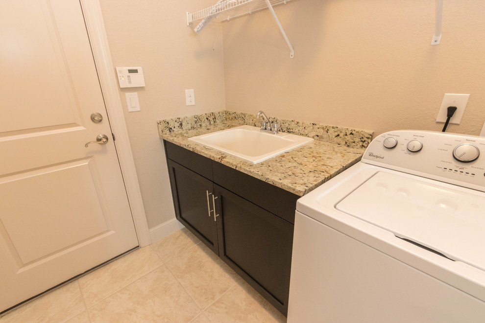 Inspiration for a mid-sized contemporary single-wall ceramic tile dedicated laundry room remodel in Miami with a drop-in sink, shaker cabinets, dark wood cabinets, granite countertops, beige walls and a side-by-side washer/dryer