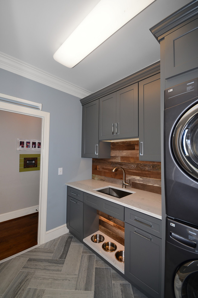 Medium sized farmhouse separated utility room in Charlotte with a submerged sink, shaker cabinets, grey cabinets, engineered stone countertops, blue walls, limestone flooring and a stacked washer and dryer.