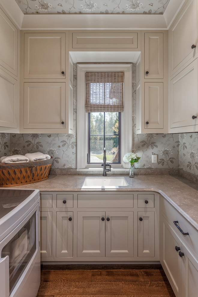 Medium sized mediterranean u-shaped separated utility room in Other with beige cabinets, a side by side washer and dryer, a submerged sink, shaker cabinets, granite worktops, medium hardwood flooring, brown floors and grey walls.