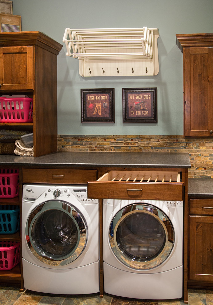 Bild på en mellanstor vintage tvättstuga, med skåp i shakerstil, skåp i mörkt trä, granitbänkskiva, blå väggar, skiffergolv och en tvättmaskin och torktumlare bredvid varandra