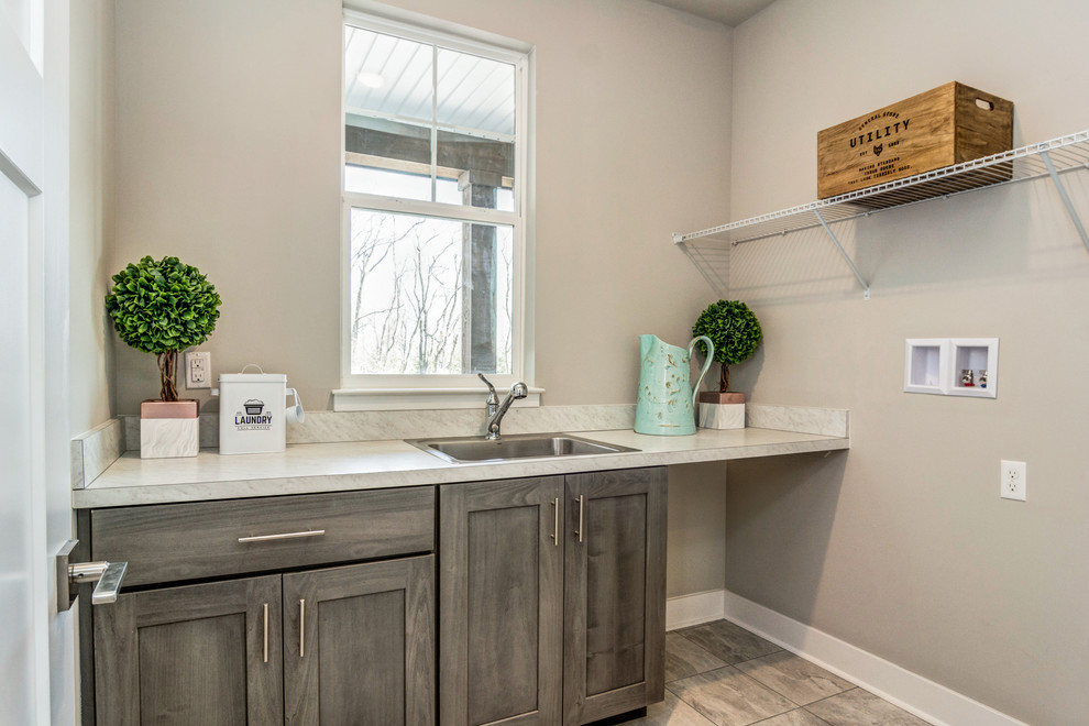 Inspiration for a mid-sized country galley ceramic tile and gray floor dedicated laundry room remodel in Other with a single-bowl sink, shaker cabinets, medium tone wood cabinets, laminate countertops, gray walls, a side-by-side washer/dryer and gray countertops