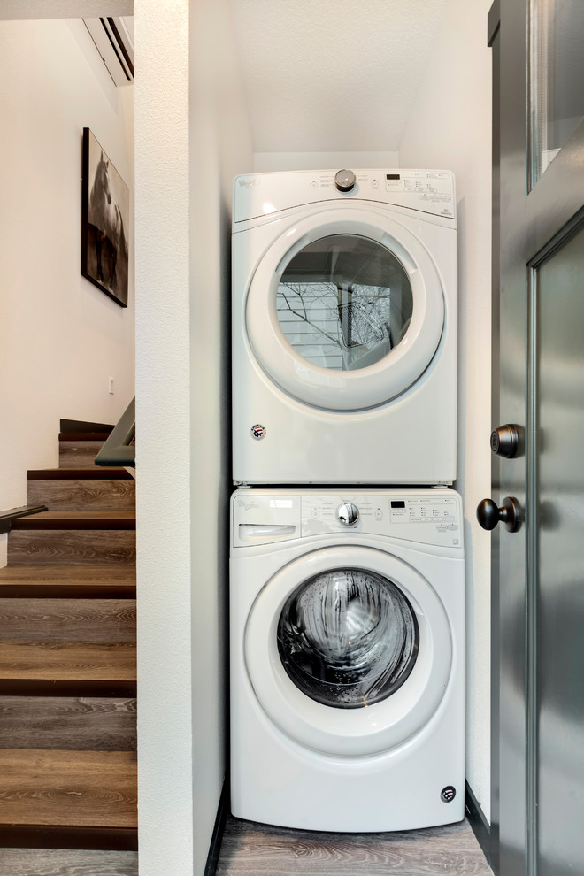 Ispirazione per una piccola sala lavanderia moderna con pareti bianche, pavimento in laminato, lavatrice e asciugatrice a colonna e pavimento grigio