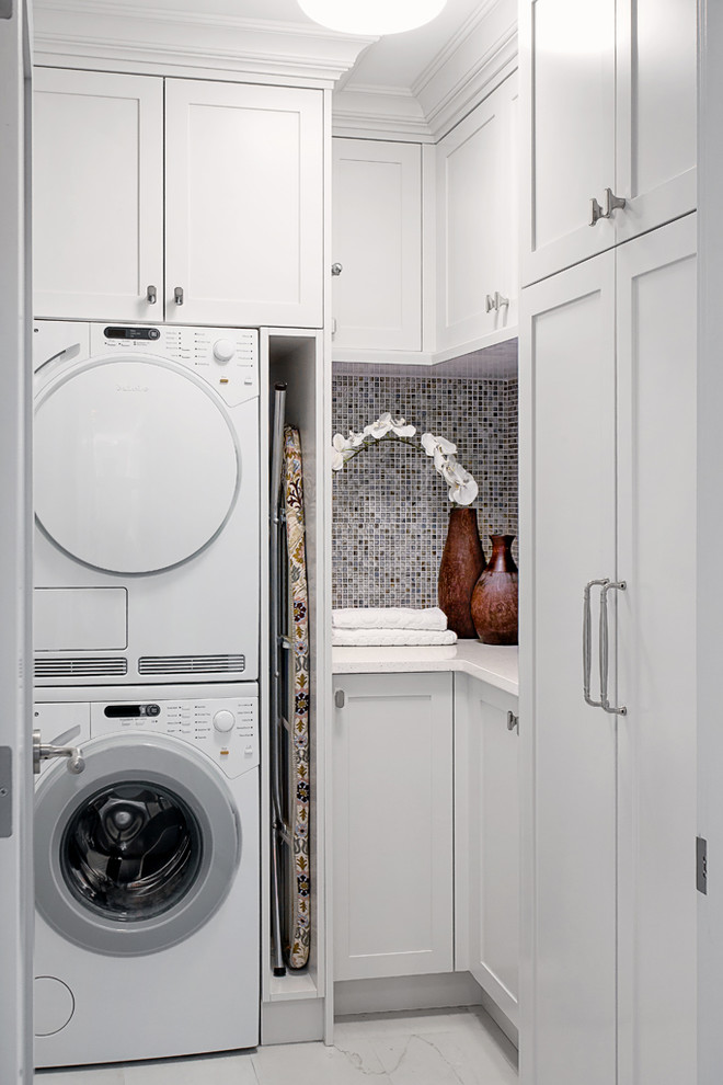 Ejemplo de cuarto de lavado en L clásico con armarios estilo shaker, puertas de armario blancas y lavadora y secadora apiladas