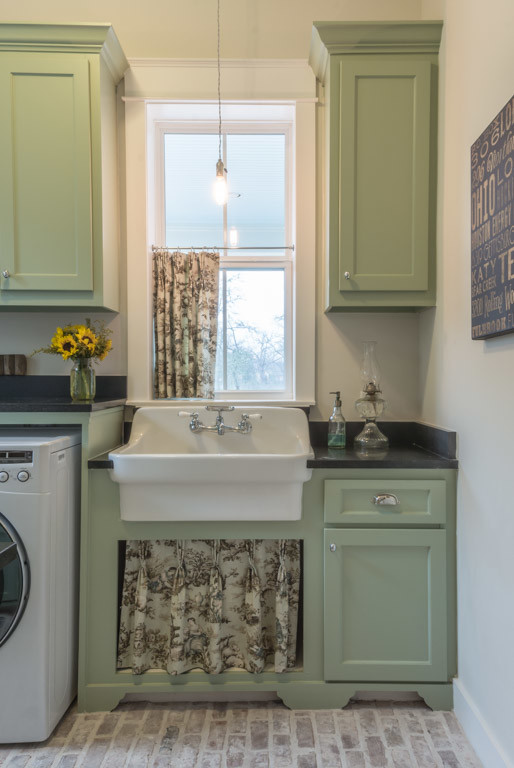 Idéer för stora vintage u-formade tvättstugor enbart för tvätt, med en rustik diskho, skåp i shakerstil, gröna skåp, granitbänkskiva, beige väggar, tegelgolv och en tvättmaskin och torktumlare bredvid varandra