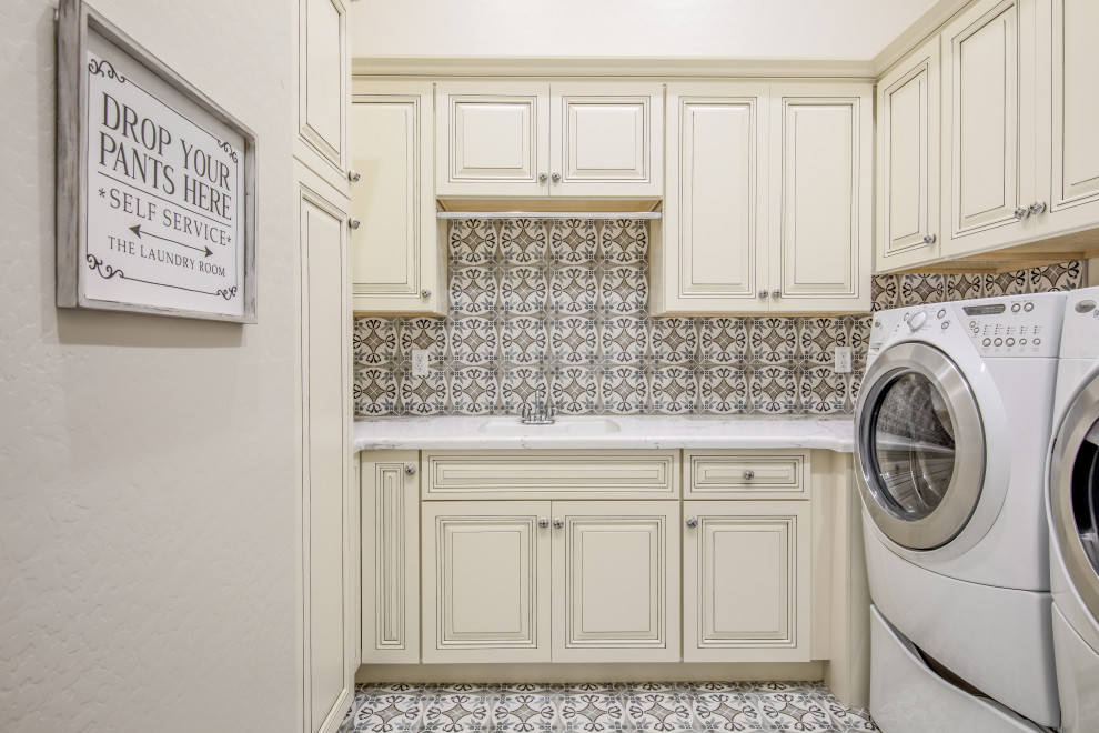 Medium sized traditional u-shaped separated utility room in Phoenix with a submerged sink, raised-panel cabinets, white cabinets, beige walls, ceramic flooring, a side by side washer and dryer, beige floors and white worktops.