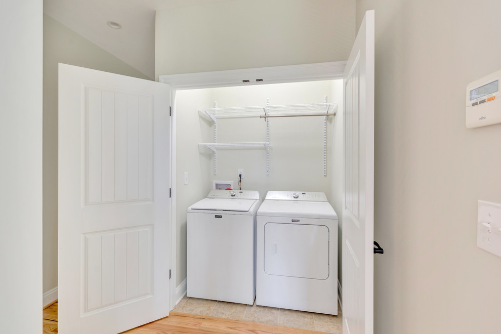 Immagine di un ripostiglio-lavanderia classico di medie dimensioni con pareti beige, pavimento con piastrelle in ceramica, lavatrice e asciugatrice affiancate e pavimento beige