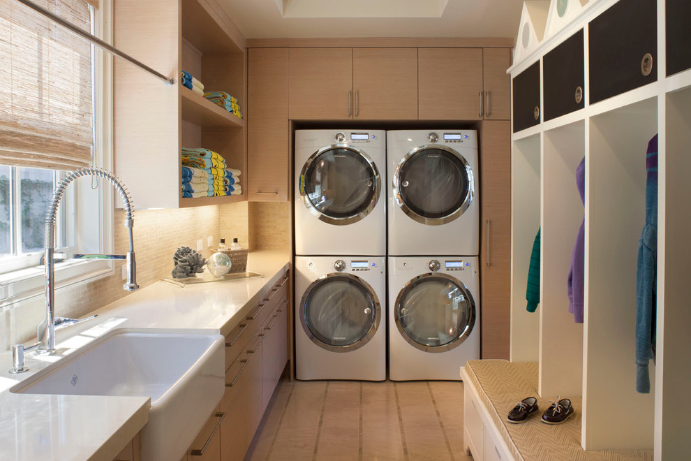 Elegant laundry room photo in Los Angeles with a farmhouse sink, light wood cabinets and a stacked washer/dryer