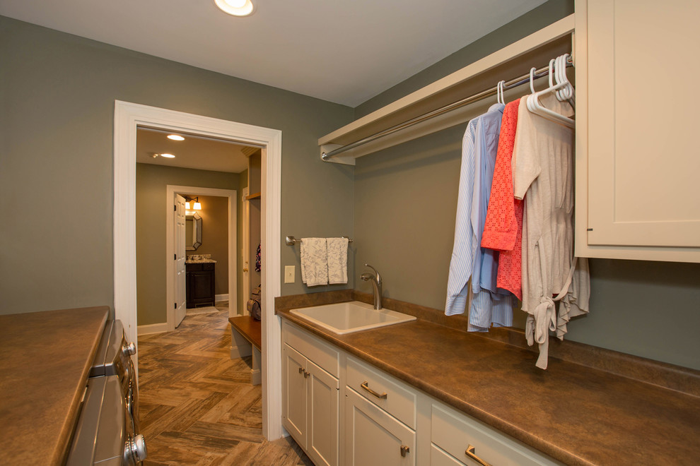 Medium sized traditional galley separated utility room in Cincinnati with a built-in sink, shaker cabinets, white cabinets, green walls, a side by side washer and dryer and brown floors.