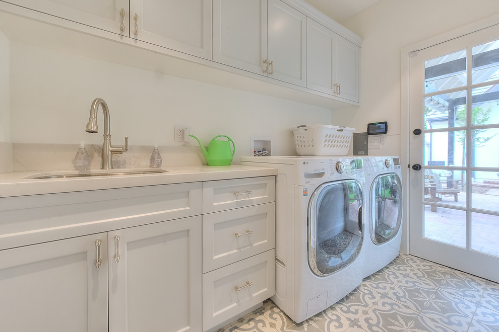 This is an example of a medium sized traditional single-wall separated utility room in Los Angeles with a submerged sink, recessed-panel cabinets, white cabinets, engineered stone countertops, white walls, concrete flooring, a side by side washer and dryer, grey floors and grey worktops.