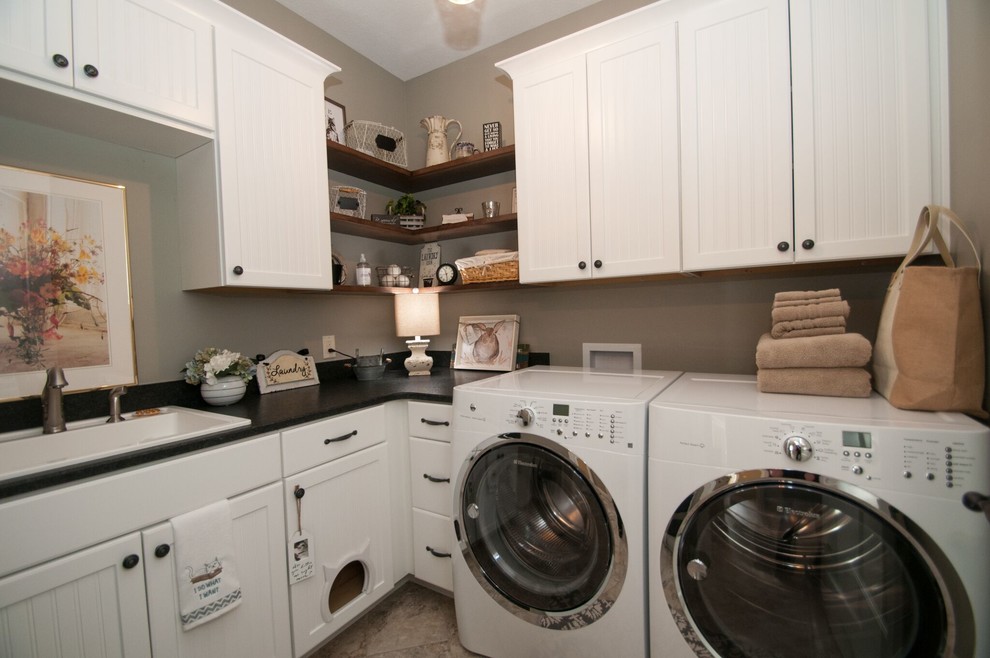 Exempel på en liten klassisk l-formad tvättstuga, med en nedsänkt diskho, skåp i shakerstil, vita skåp, granitbänkskiva, grå väggar, klinkergolv i porslin, en tvättmaskin och torktumlare bredvid varandra och beiget golv
