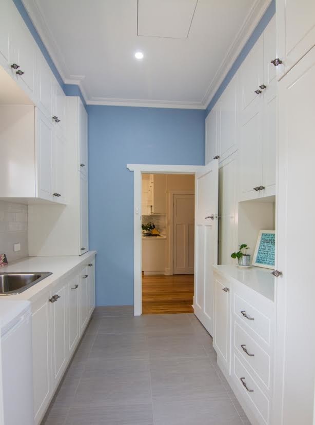 Zweizeilige, Mittelgroße Klassische Waschküche mit Waschbecken, Schrankfronten im Shaker-Stil, weißen Schränken, Granit-Arbeitsplatte, blauer Wandfarbe, Travertin und beigem Boden in Melbourne