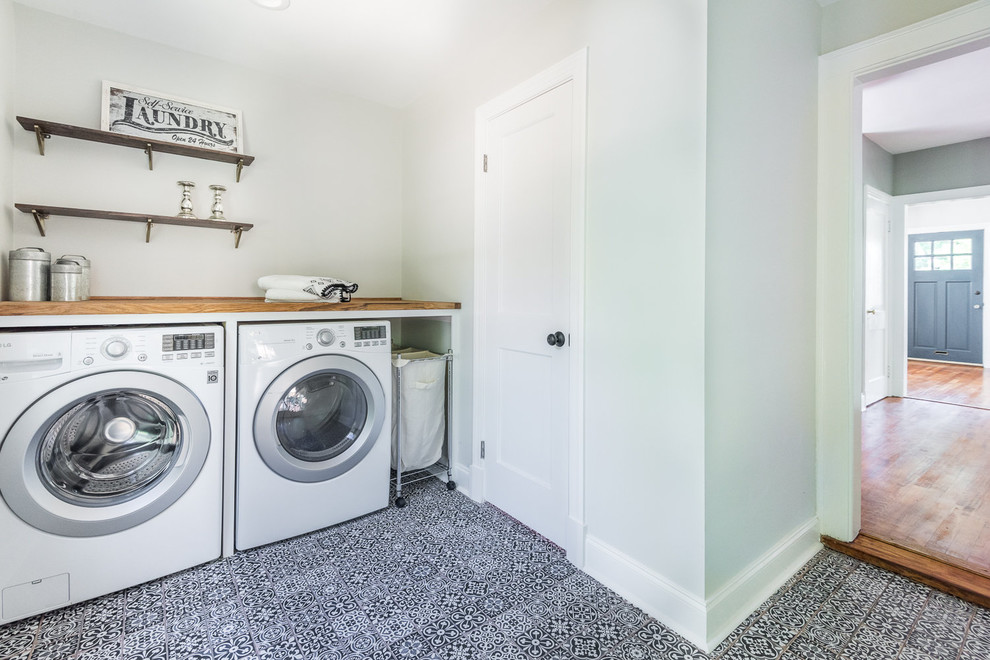 Immagine di una grande sala lavanderia tradizionale con top in legno, pareti bianche, lavatrice e asciugatrice affiancate e pavimento blu