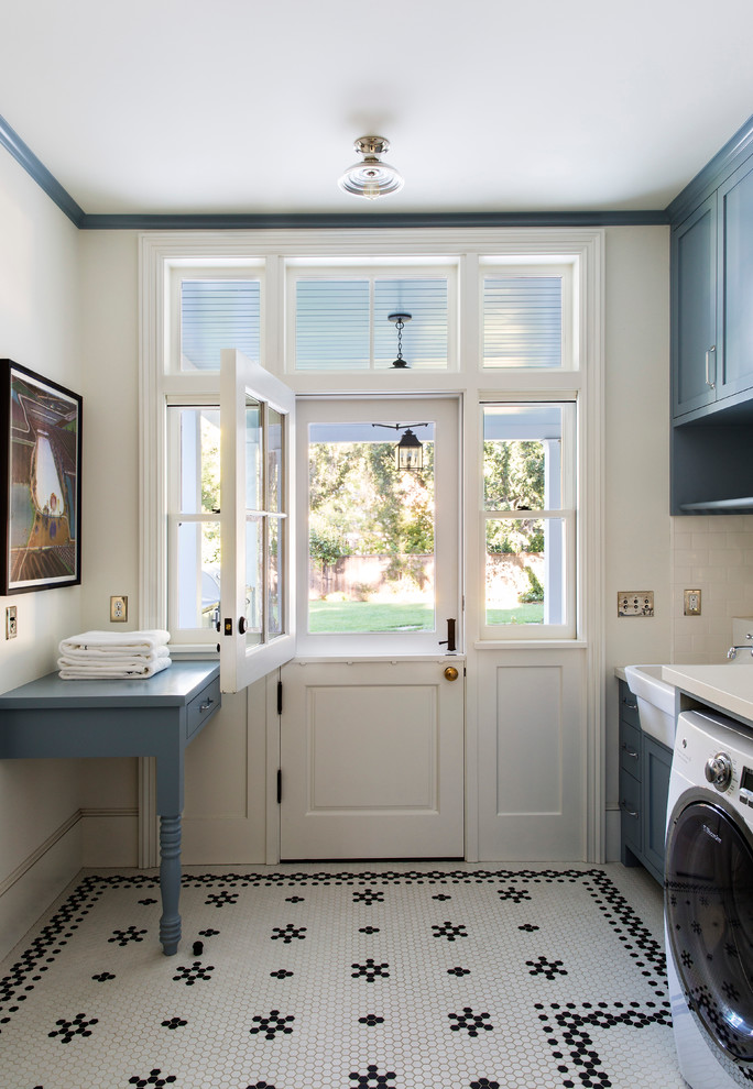 Ispirazione per una sala lavanderia classica con ante in stile shaker, ante blu, lavello stile country, pareti bianche e pavimento multicolore