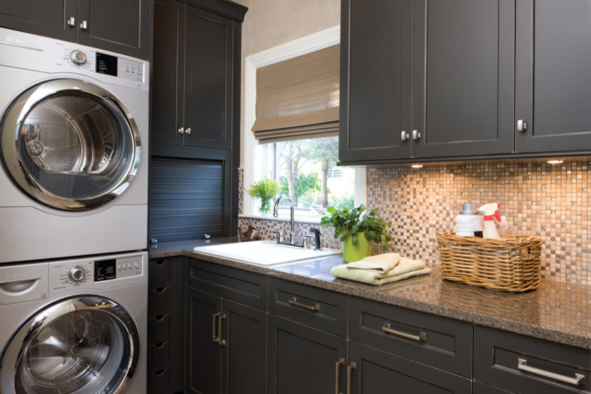 Inspiration for a large timeless l-shaped dedicated laundry room remodel in Other with a drop-in sink, shaker cabinets, black cabinets, granite countertops, brown walls and a stacked washer/dryer