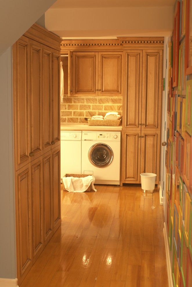 Example of a small classic single-wall light wood floor utility room design in New York with raised-panel cabinets, marble countertops, a side-by-side washer/dryer and medium tone wood cabinets