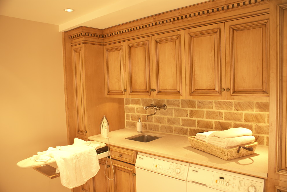 Inspiration for a small classic single-wall utility room in New York with a single-bowl sink, raised-panel cabinets, marble worktops, a side by side washer and dryer, medium wood cabinets and brown walls.