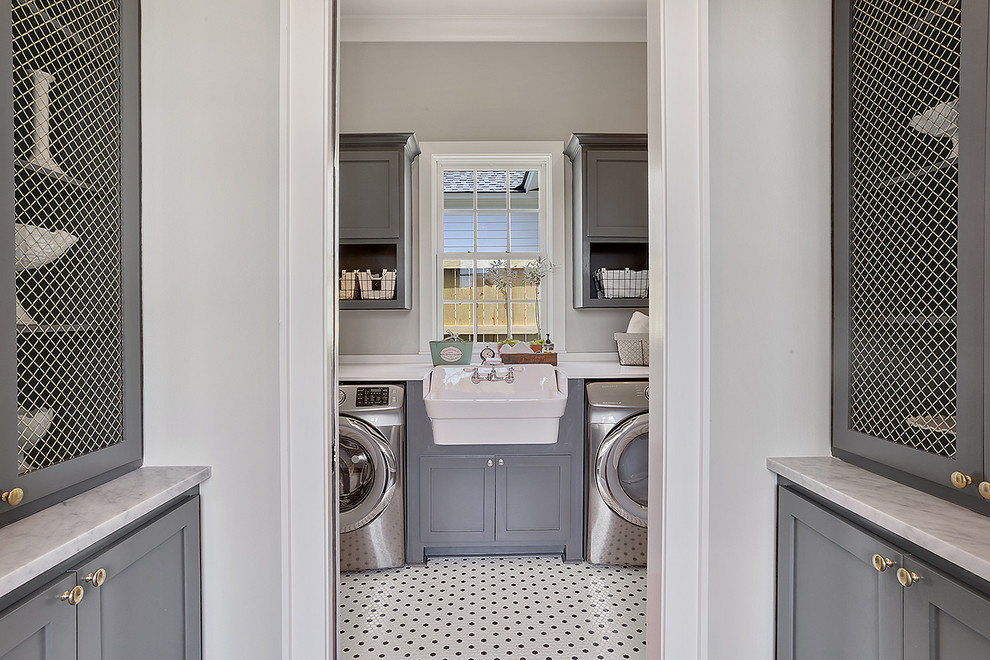Utility room - large traditional single-wall utility room idea in New Orleans with a farmhouse sink, recessed-panel cabinets, gray cabinets, gray walls, a side-by-side washer/dryer and quartz countertops
