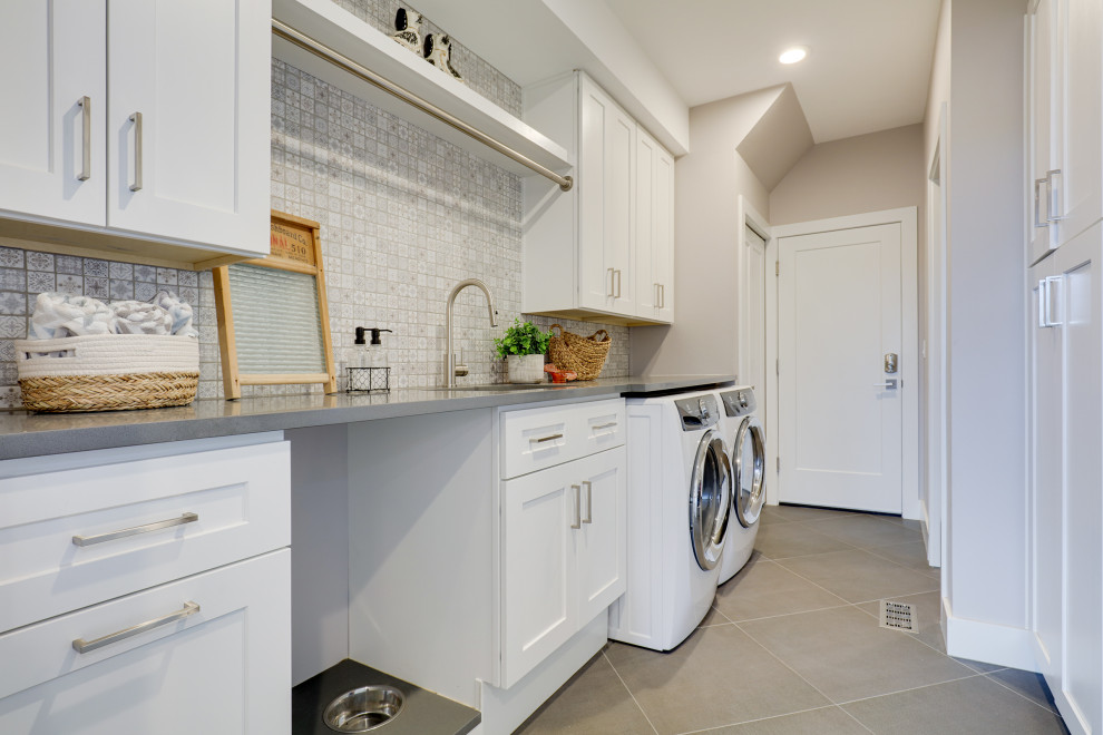 Bild på en stor vintage grå linjär grått tvättstuga enbart för tvätt, med en undermonterad diskho, skåp i shakerstil, vita skåp, bänkskiva i kvarts, beige väggar, klinkergolv i porslin, en tvättmaskin och torktumlare bredvid varandra och grått golv
