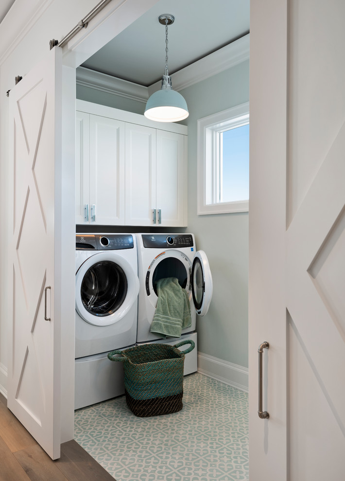 Imagen de cuarto de lavado tradicional renovado con armarios con paneles empotrados, puertas de armario blancas, paredes grises, lavadora y secadora juntas y suelo azul