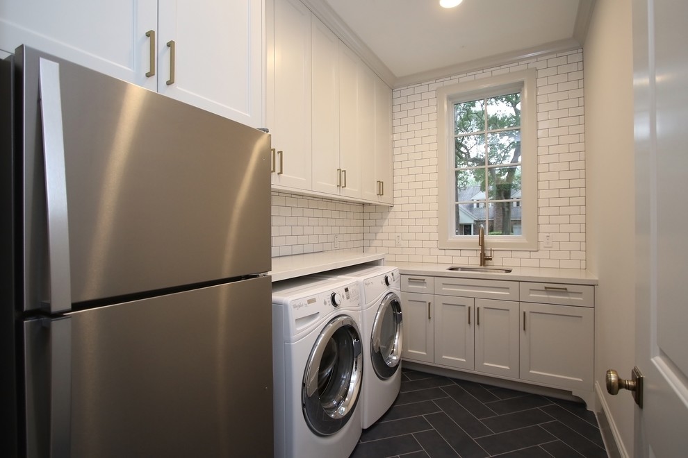 Mid-sized transitional l-shaped concrete floor and black floor dedicated laundry room photo in Houston with an undermount sink, shaker cabinets, white cabinets, quartz countertops, gray walls and a side-by-side washer/dryer