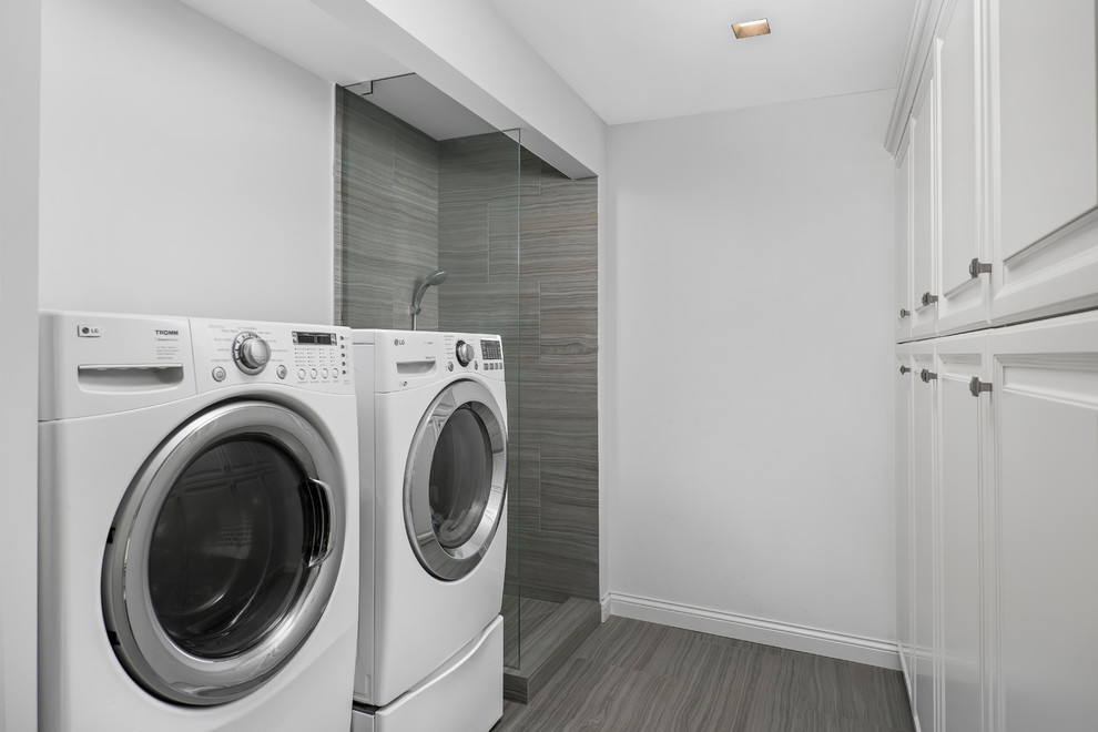 Foto di una lavanderia chic con ante bianche, pareti bianche, lavatrice e asciugatrice affiancate e pavimento grigio