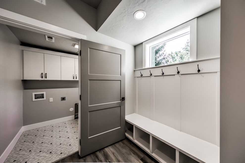 Inspiration för mellanstora klassiska linjära grått tvättstugor enbart för tvätt, med släta luckor, vita skåp, grå väggar, mörkt trägolv och brunt golv