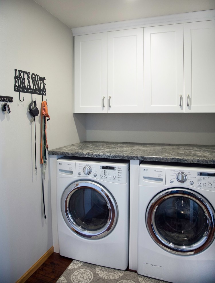 Esempio di una piccola sala lavanderia classica con ante bianche, top in granito, pareti grigie, parquet scuro, lavatrice e asciugatrice affiancate, pavimento marrone e top grigio