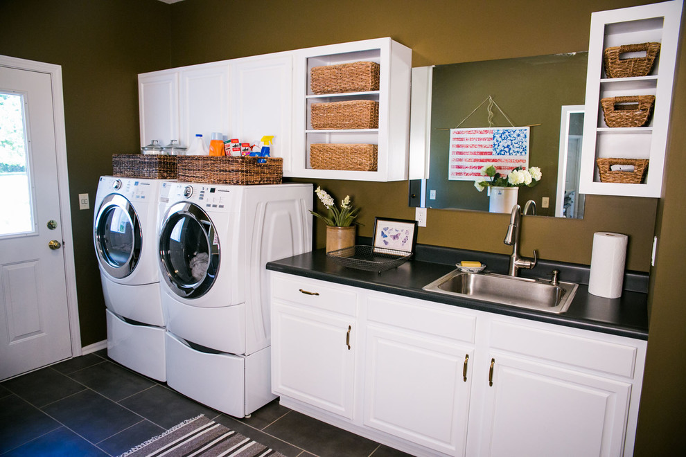 Large classic single-wall separated utility room in St Louis with a built-in sink, raised-panel cabinets, white cabinets, laminate countertops, green walls, vinyl flooring and a side by side washer and dryer.