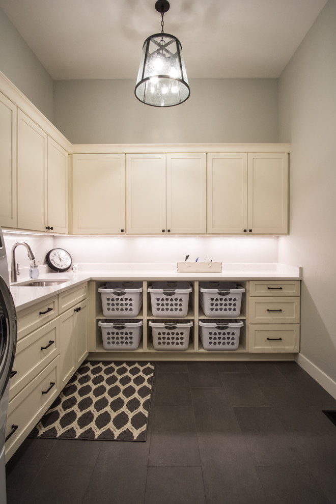 Idéer för att renovera en stor vintage vita l-formad vitt tvättstuga enbart för tvätt, med en undermonterad diskho, skåp i shakerstil, vita skåp, bänkskiva i kvarts, grå väggar, skiffergolv, en tvättmaskin och torktumlare bredvid varandra och grått golv