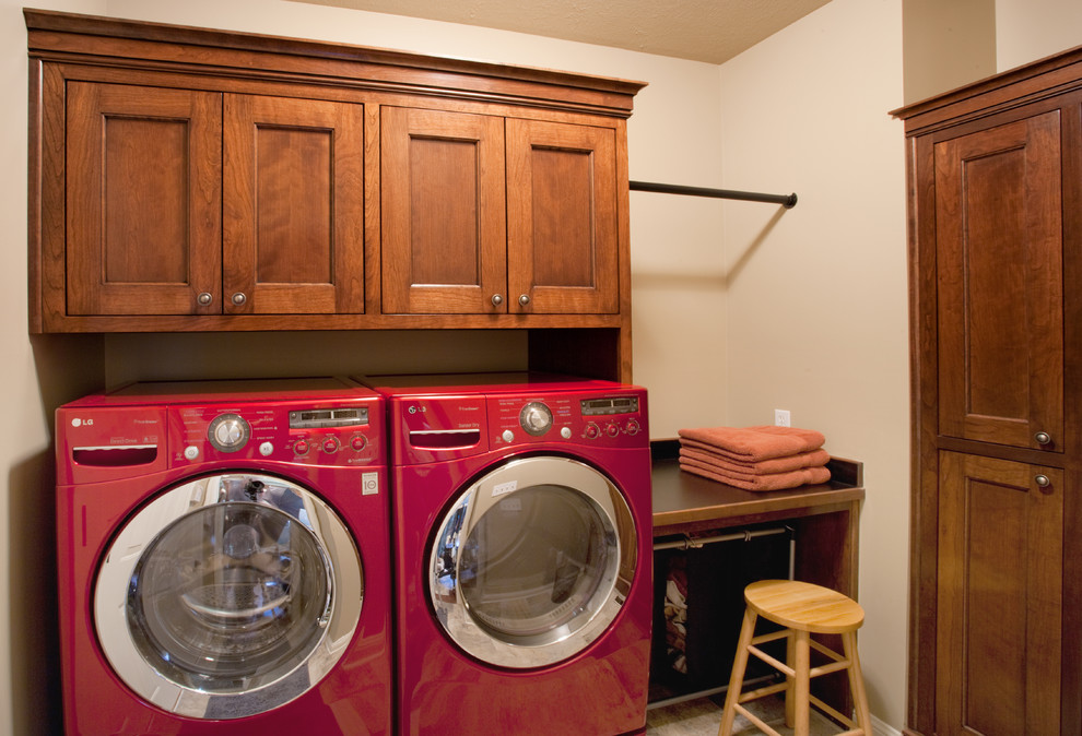 Mittelgroße Klassische Waschküche in L-Form mit Kassettenfronten, dunklen Holzschränken, beiger Wandfarbe, Porzellan-Bodenfliesen und Waschmaschine und Trockner nebeneinander in Sonstige