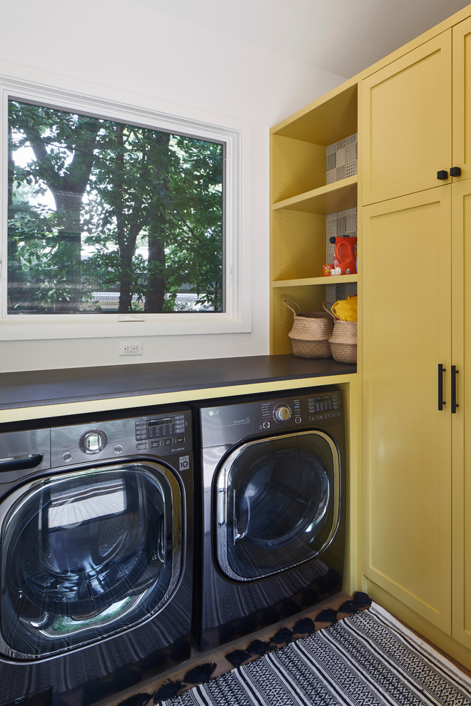 オースティンにある高級な中くらいなトランジショナルスタイルのおしゃれな洗濯室 (L型、シェーカースタイル扉のキャビネット、黄色いキャビネット、白い壁、左右配置の洗濯機・乾燥機、グレーのキッチンカウンター) の写真