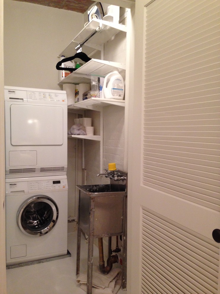 Design ideas for a small contemporary laundry cupboard in New York with an utility sink, white walls and a stacked washer and dryer.