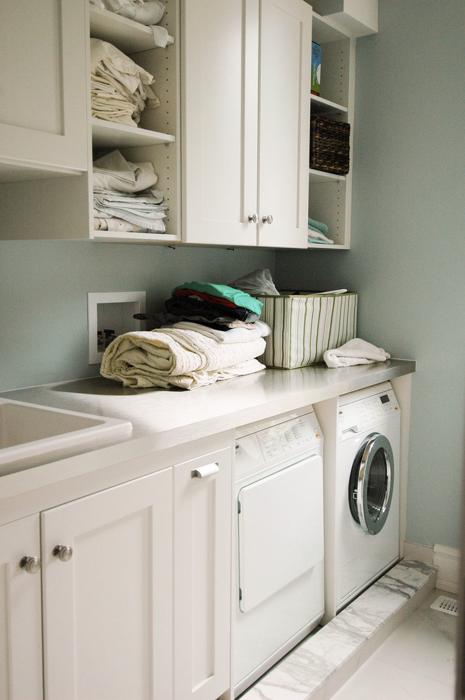 Immagine di una lavanderia multiuso chic di medie dimensioni con lavello da incasso, ante in stile shaker, ante bianche, pareti blu e lavatrice e asciugatrice affiancate