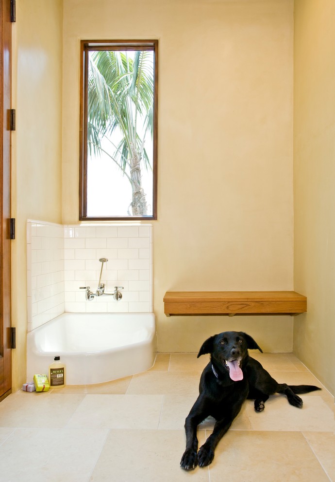 This is an example of a large world-inspired l-shaped utility room in Santa Barbara with yellow walls, beige floors, a submerged sink, shaker cabinets, white cabinets, travertine flooring, a side by side washer and dryer and white worktops.