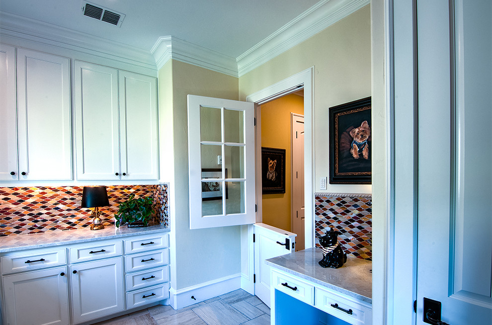 Inspiration for a large mediterranean l-shaped utility room in Dallas with recessed-panel cabinets, white cabinets, granite worktops, beige walls, limestone flooring and a side by side washer and dryer.