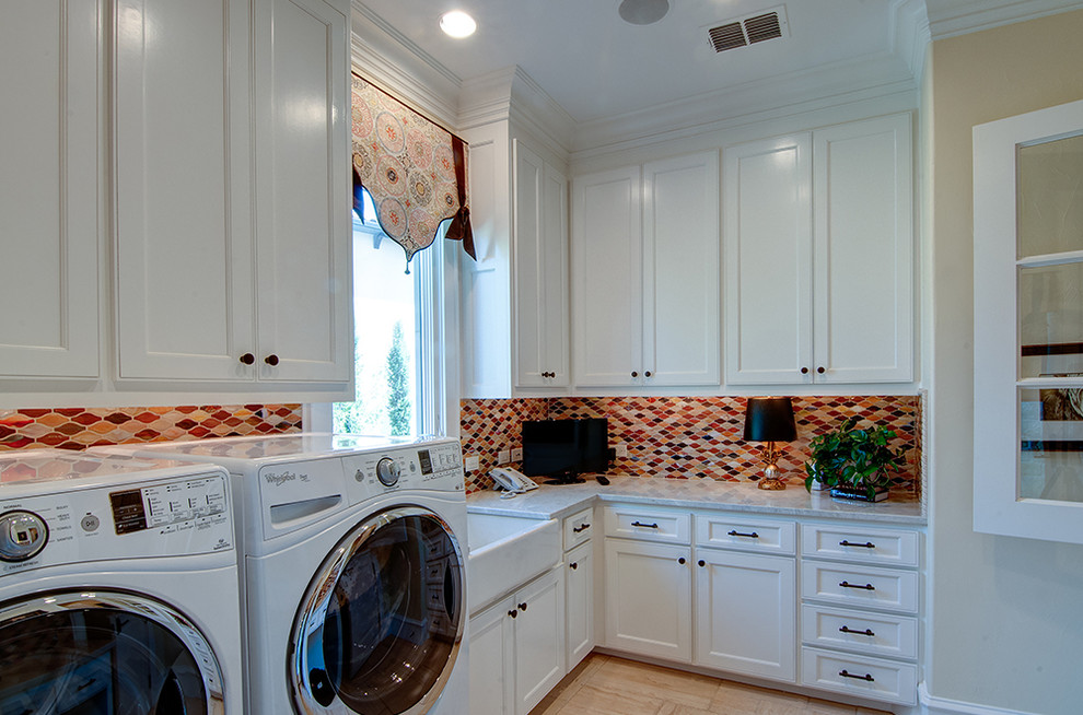 Utility room - large mediterranean l-shaped limestone floor utility room idea in Dallas with a farmhouse sink, shaker cabinets, white cabinets, granite countertops, beige walls and a side-by-side washer/dryer