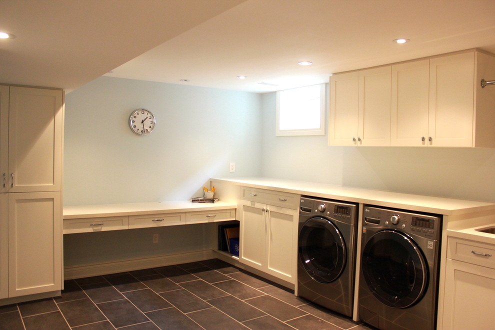 This is an example of a medium sized classic l-shaped utility room in Toronto with white cabinets, a side by side washer and dryer, shaker cabinets, white walls, a single-bowl sink, composite countertops, porcelain flooring and grey floors.