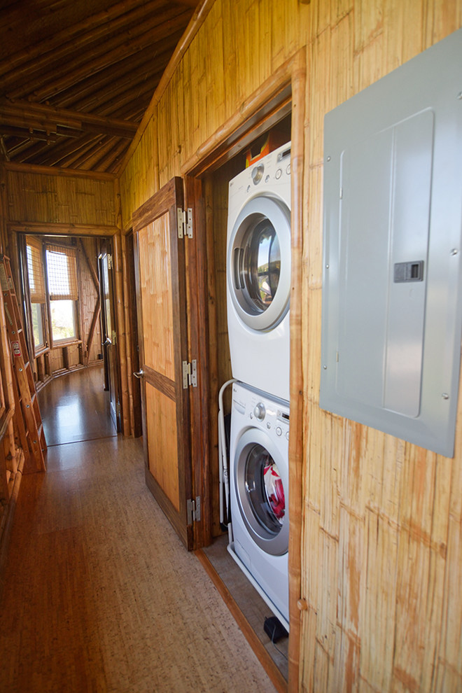 Ispirazione per un ripostiglio-lavanderia tropicale con pavimento in sughero e lavatrice e asciugatrice a colonna