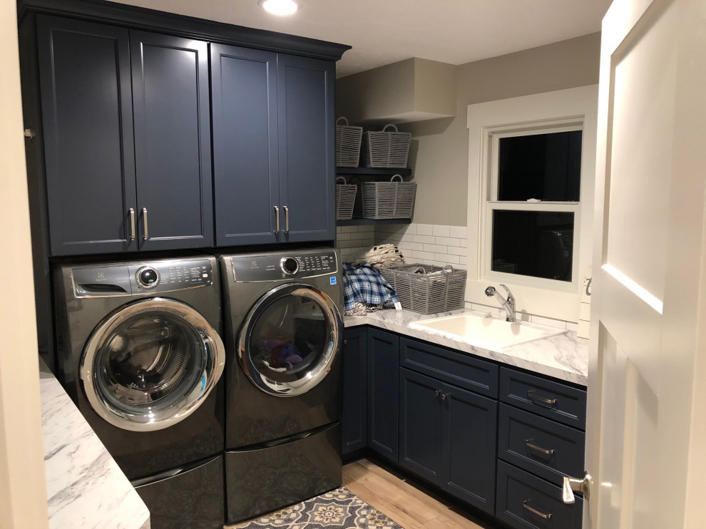 Inspiration for a small transitional l-shaped vinyl floor and beige floor dedicated laundry room remodel in Grand Rapids with recessed-panel cabinets, blue cabinets, laminate countertops, a side-by-side washer/dryer, multicolored countertops, a drop-in sink and gray walls