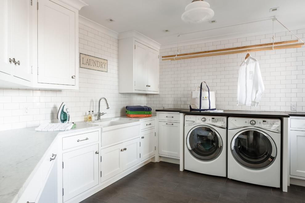 This is an example of a traditional u-shaped utility room in New York with a belfast sink, recessed-panel cabinets, white cabinets, a side by side washer and dryer and white worktops.