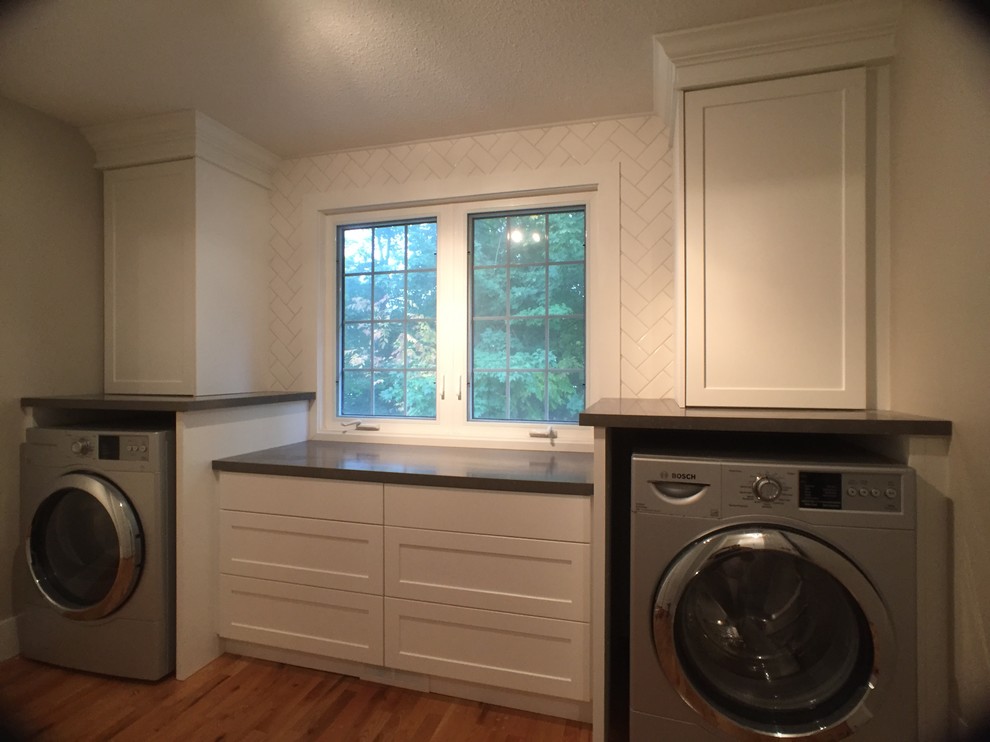 Ejemplo de lavadero lineal tradicional renovado de tamaño medio con puertas de armario blancas, encimera de laminado, suelo de madera clara y lavadora y secadora juntas
