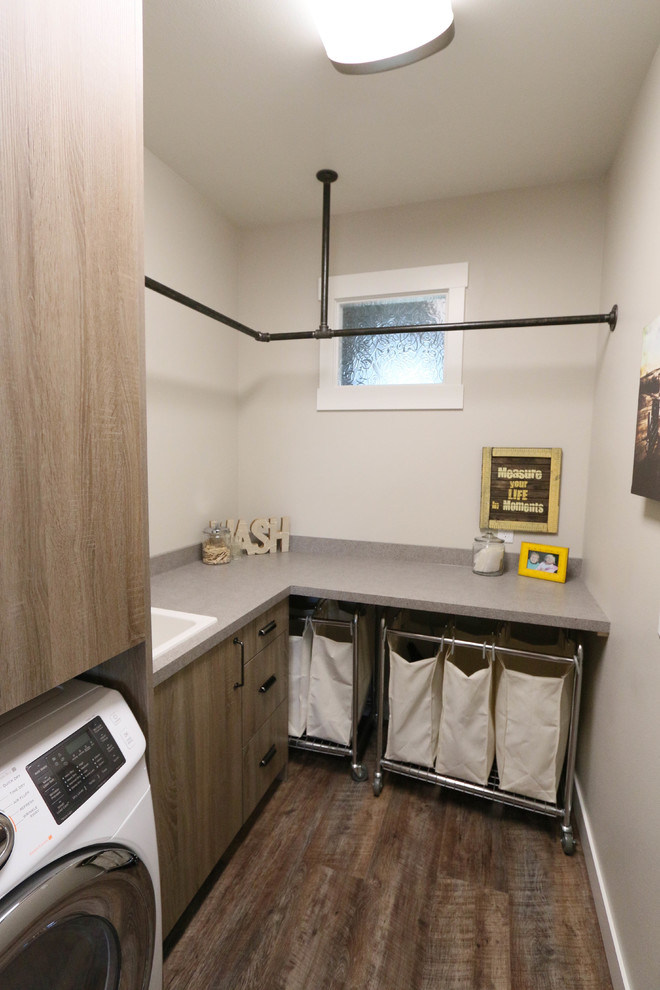 This is an example of a medium sized urban l-shaped separated utility room in Other with a built-in sink, flat-panel cabinets, medium wood cabinets, laminate countertops, grey walls, vinyl flooring and a side by side washer and dryer.